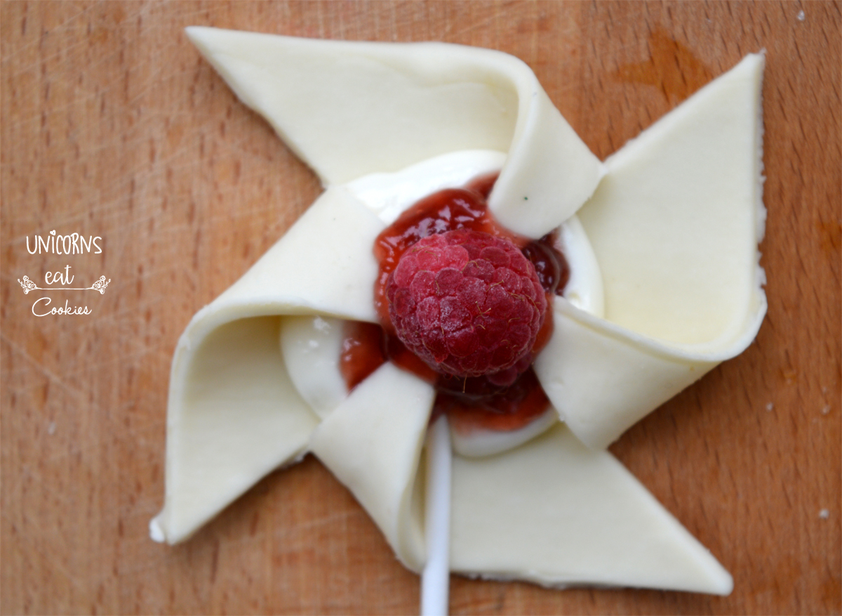 Facile e veloce ricetta per preparare queste girandole di pasta sfoglia ripiene di marmellata, crema dolce al formaggio e lamponi freschi.
