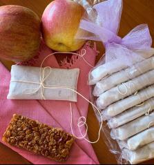 nell'angolo in basso a sinistra barretta muesli come da ricetta. Intorno set di barrette avvolte ciascuna in carta da forno e legate con spago come piccoli pacchettini regalo