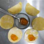 preparazione dei fagottini, con sei dischi di impasto. Su due dischi è già visibile il ripieno di marmellata. I dischi sono disposti intorno a un contenitore tondo, in mezzo al quale è poggiato un cucchiaio colmo di marmellata con cui procedere alla farcitura