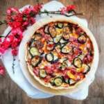 Immagine della torta salata vista dall'alto, con tuttre le note di colore date dagli ingredienti del ripieno: zucchine tagliate a rondelle, scalogno, prosciutto e formaggio