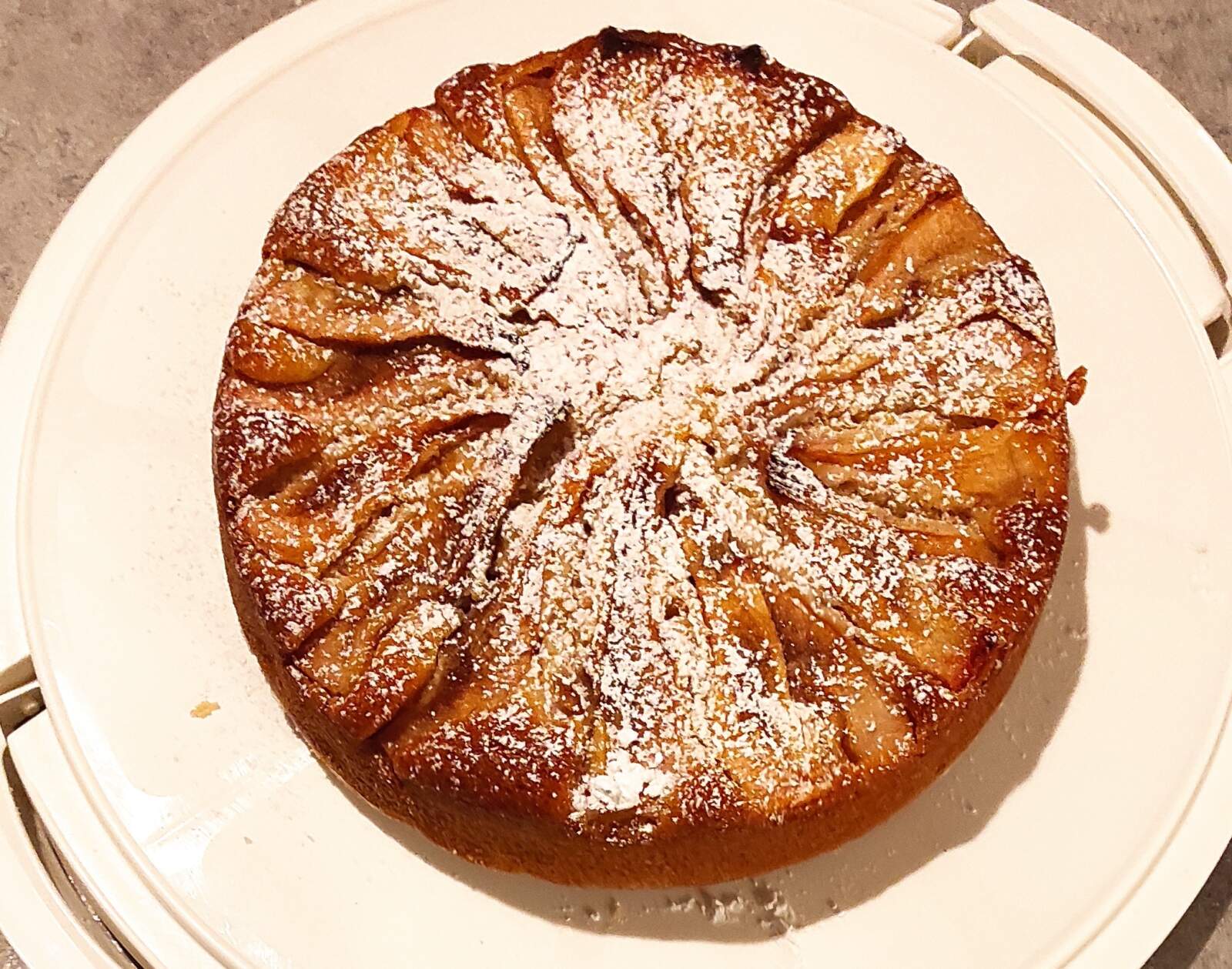 torta vista dall'alto con fettine di mele in superficie e spolverata di zucchero a velo